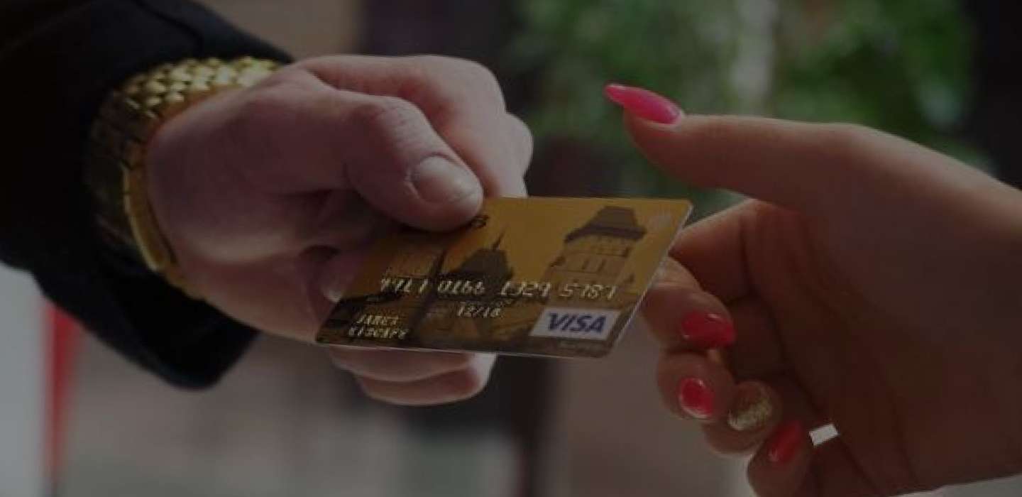 Photo of one person handing a credit card to another person that is zoomed in on just their hands.