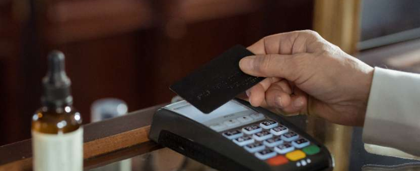 A male hand swiping a credit card through a machine