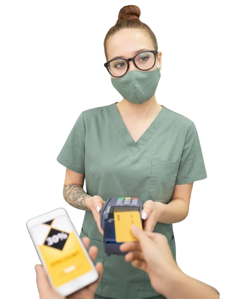 A customer uses a credit card and a mobile discount code to pay a masked pharmacist at a pharmacy counter.